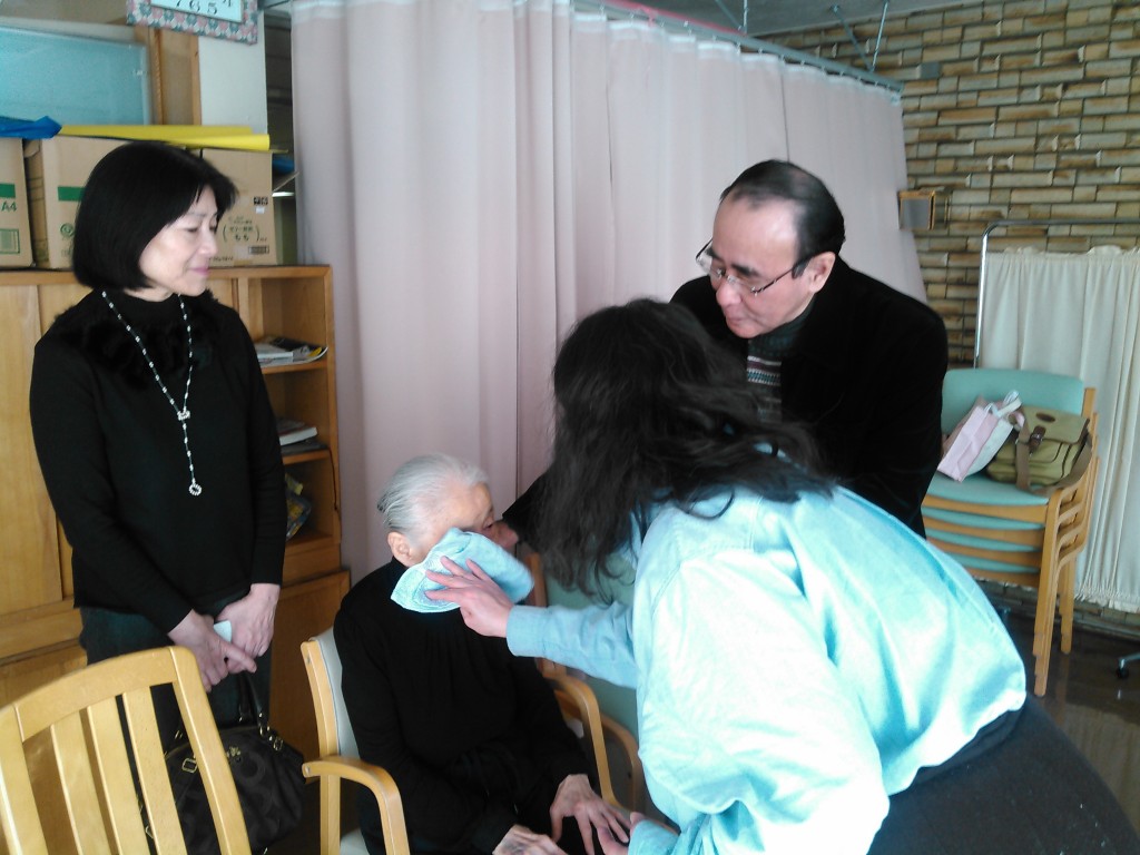 高齢（８８才）のため、みやさんは滴礼を受けました。娘晶子さんはお母さんの顔から水をふき取りました。